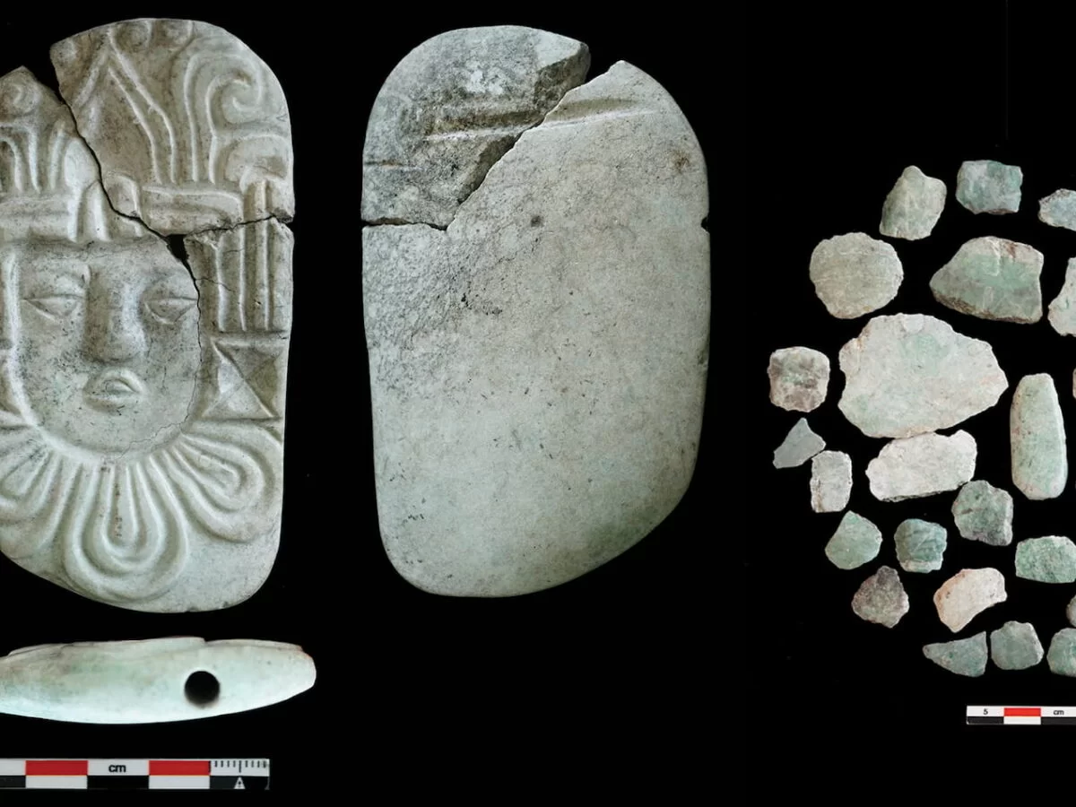 Hanging plate carved of a human head and fragments of a green stone mosaic mask found on the site